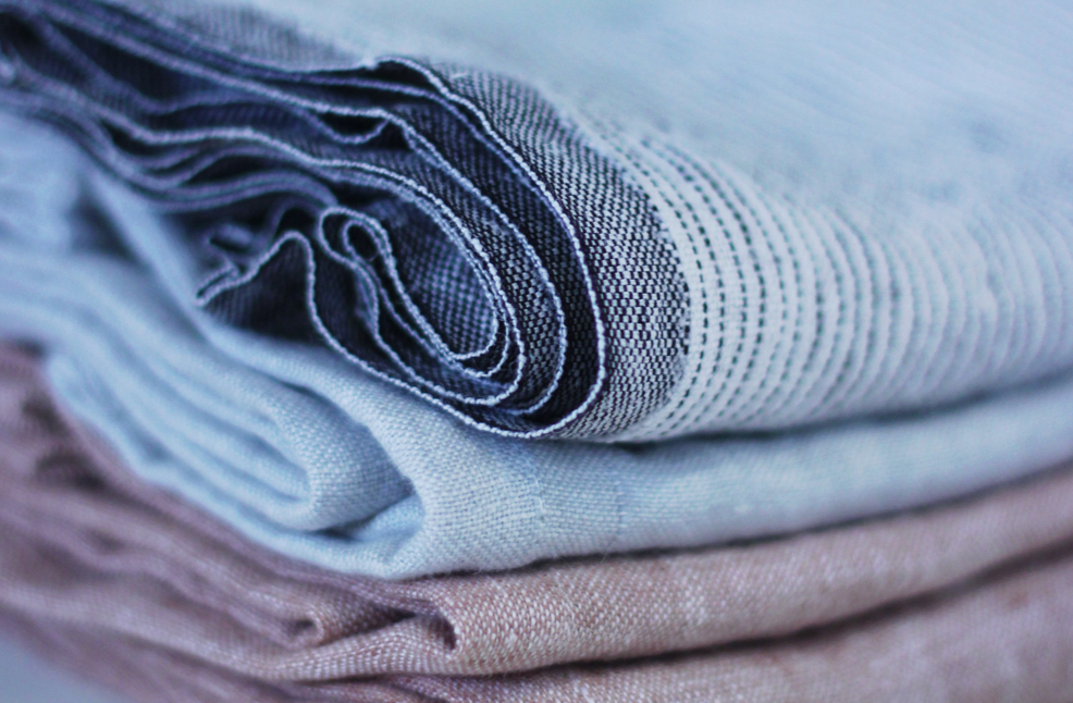 Stacks of linen fabric in a patterned blue, blue and light brown colour.
