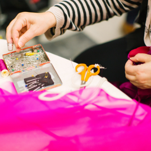 Person sewing a pink fabric.